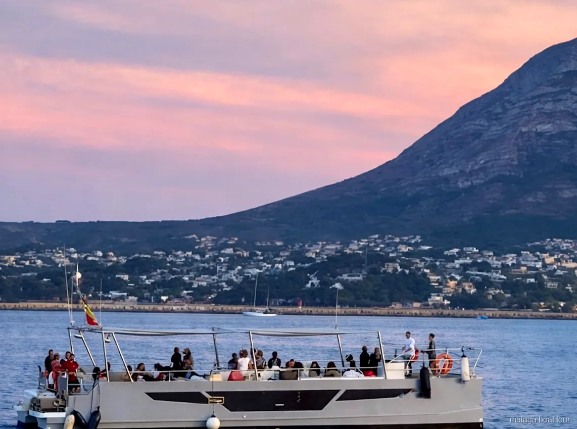 Catamarà amb passatgers a coberta al capvespre sota un cel rosat en una excursió en vaixell a Màlaga