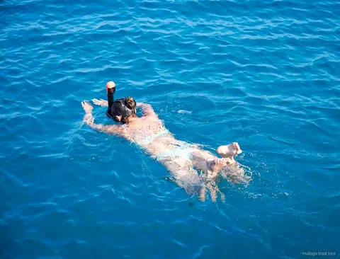 Pessoa com máscara de snorkel a flutuar em água azul e límpida num passeio de barco em Málaga