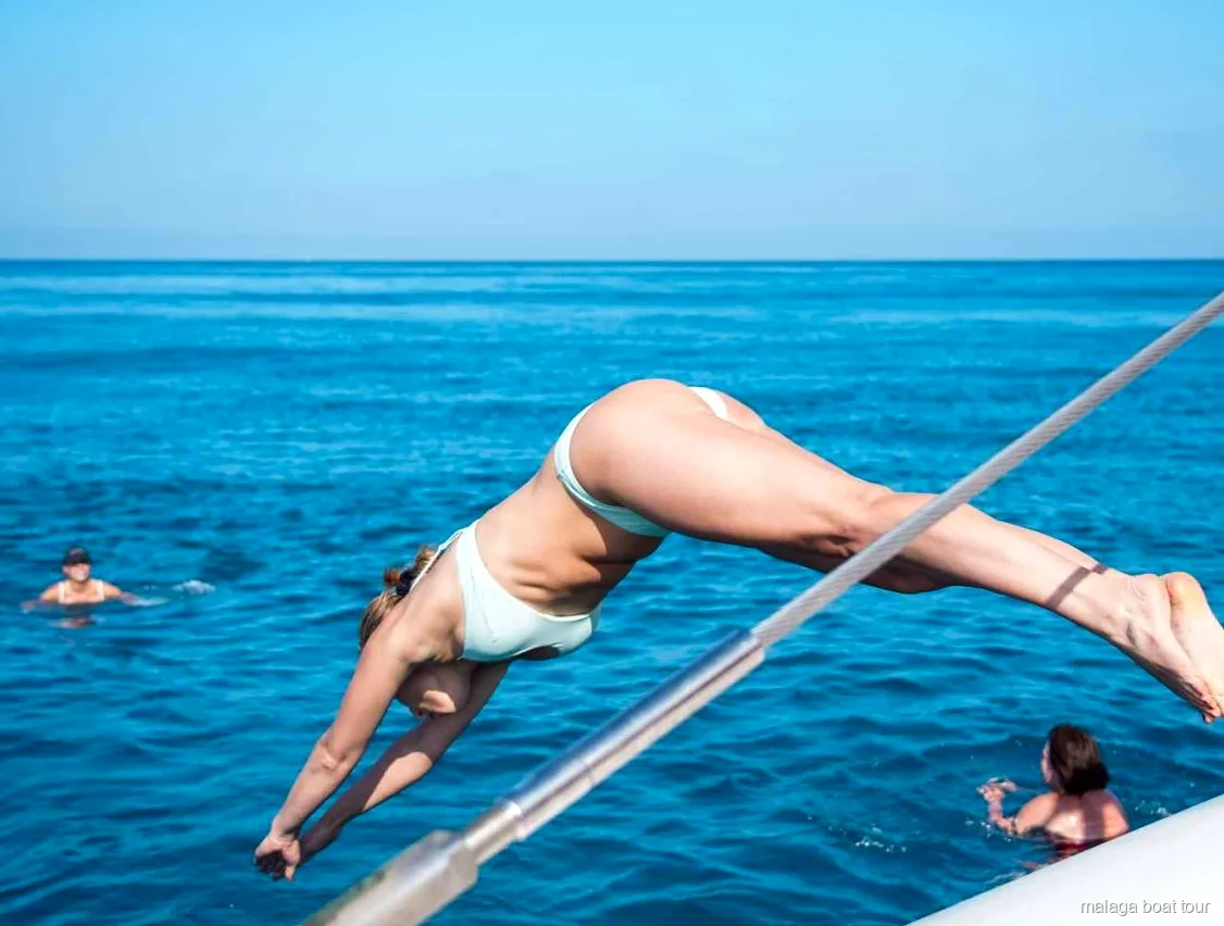 Femme plongeant du catamaran dans l'eau bleue lors d'une balade en bateau à Malaga
