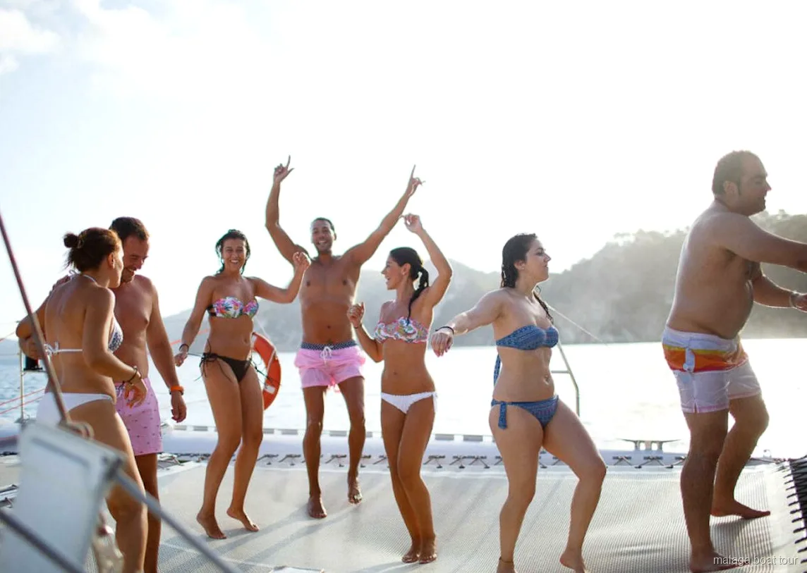 Grupo bailando descalzo en la red del catamarán en un paseo en barco por Málaga
