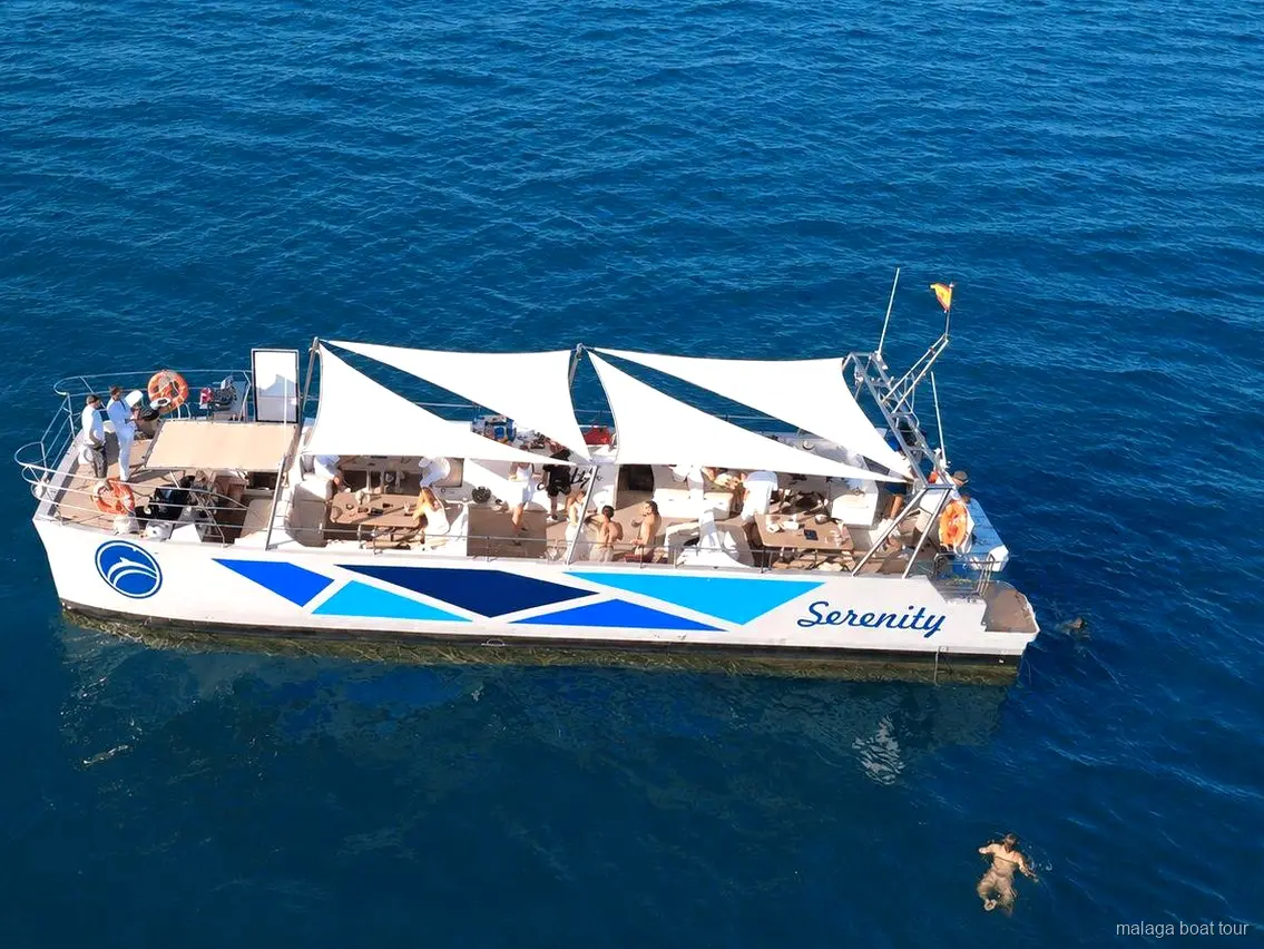Luchtfoto van de catamaran Serenity met witte zonnezeilen tijdens een boottocht in Malaga