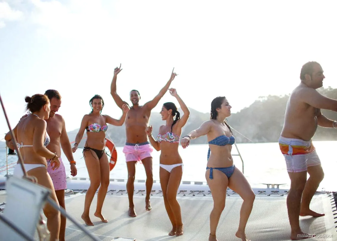 Groep danst op blote voeten op het net van de catamaran tijdens een boottocht in Malaga