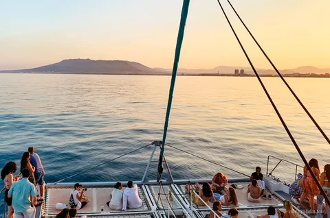 Catamaran die bij zonsondergang over de baai van Malaga vaart