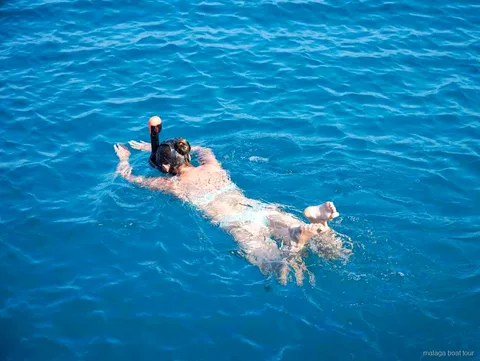 Nageuse avec masque de snorkeling flottant dans une eau bleue limpide lors d'une balade en bateau à Malaga