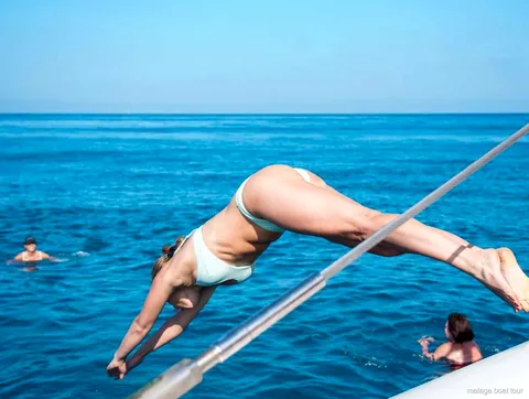Femme en plein plongeon depuis le bastingage du catamaran dans la mer lors d'une balade en bateau à Malaga