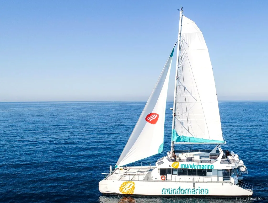Catamarano a vela con vele bianche in mare aperto e calmo durante una gita in barca a Malaga