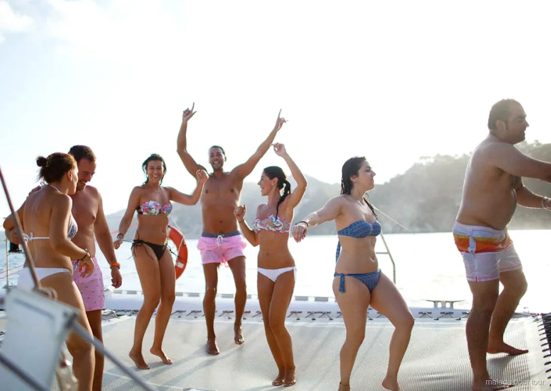 Gruppo che balla a piedi nudi sulla rete del catamarano durante una gita in barca a Malaga