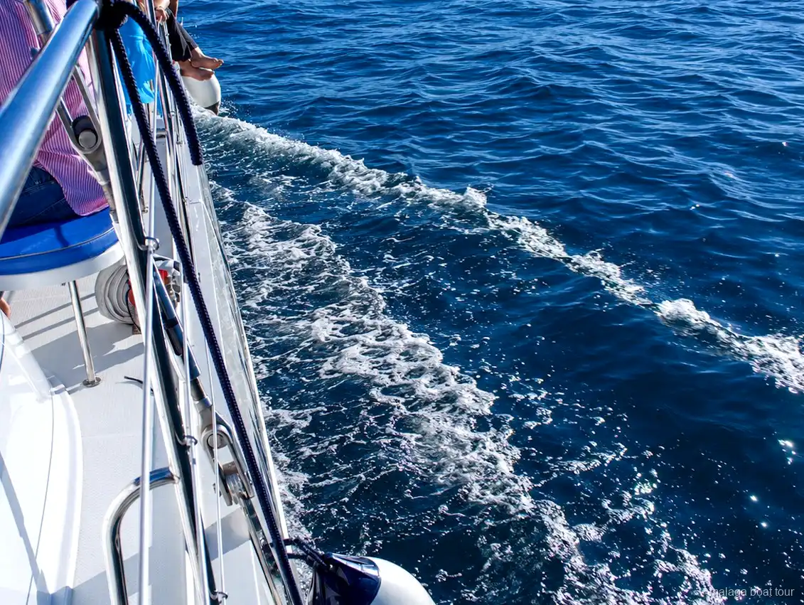 Scia di schiuma lungo lo scafo di un catamarano sul mare blu durante un malaga boat tour