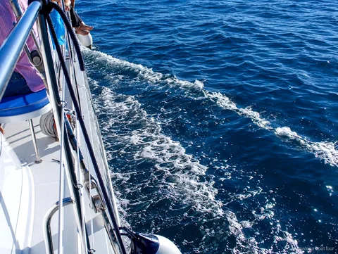 Skummande kölvatten längs skrovet på en katamaran i djupblått vatten under en malaga boat tour
