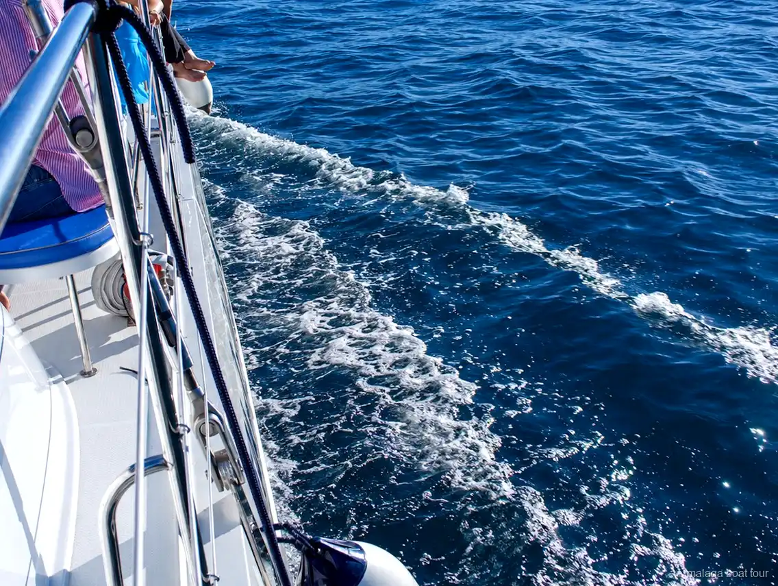 Skummande kölvatten längs skrovet på en katamaran i djupblått vatten under en malaga boat tour