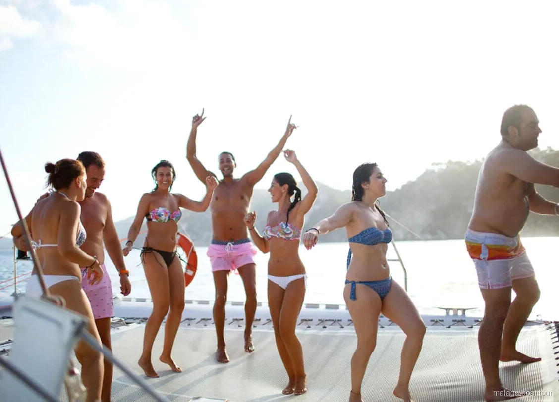 Group dancing barefoot on the catamaran trampoline net on a Malaga boat tour