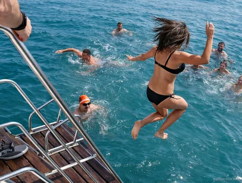 Passengers jumping off the stern into the sea at a swim stop on a Malaga boat tour
