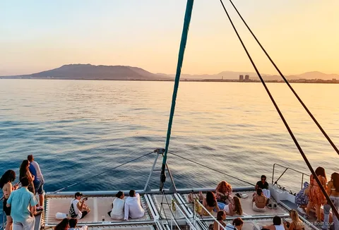 Katamaran segelt bei Sonnenuntergang über die Bucht von Malaga während der Sonnenuntergangsfahrt