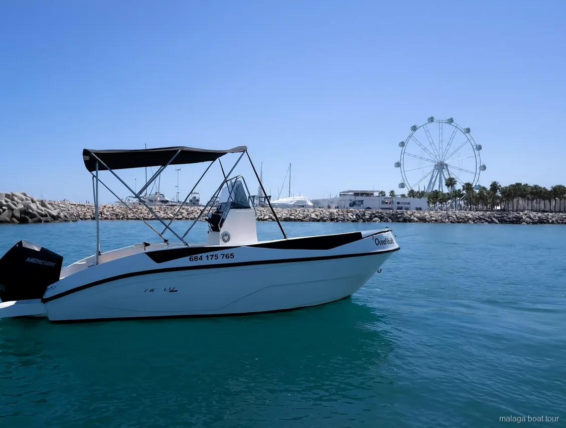 White motorboat with a canopy near the port breakwater and a Ferris wheel on a Malaga boat tour
